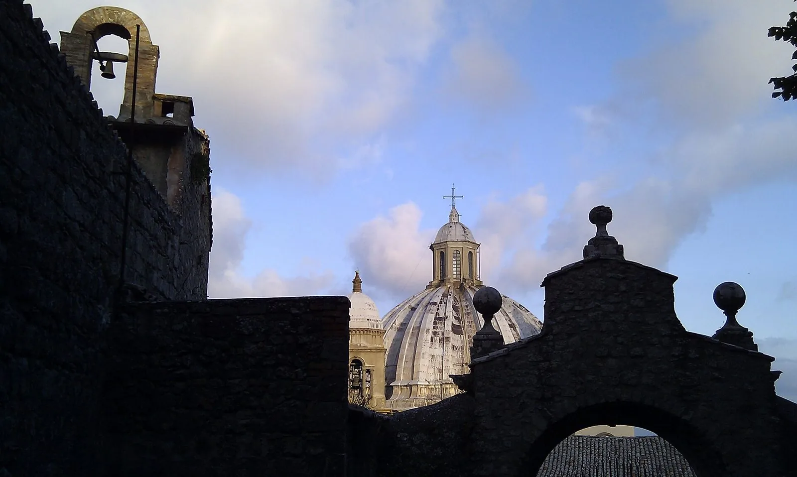 La grande cupola costolonata della cattedrale di Santa Margherita a Montefiascone vista tra mura in pietra e un arco