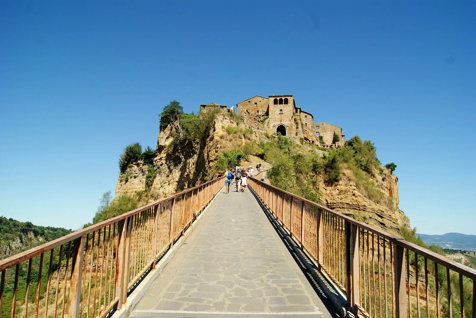 Il ponte pedonale in salita che conduce a Civita di Bagnoregio, con il borgo sulla rupe di tufo sotto un cielo blu